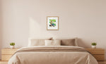 Plavi bicikl – framed drawing (approx. 39 × 45 cm) shown at true scale above a double bed